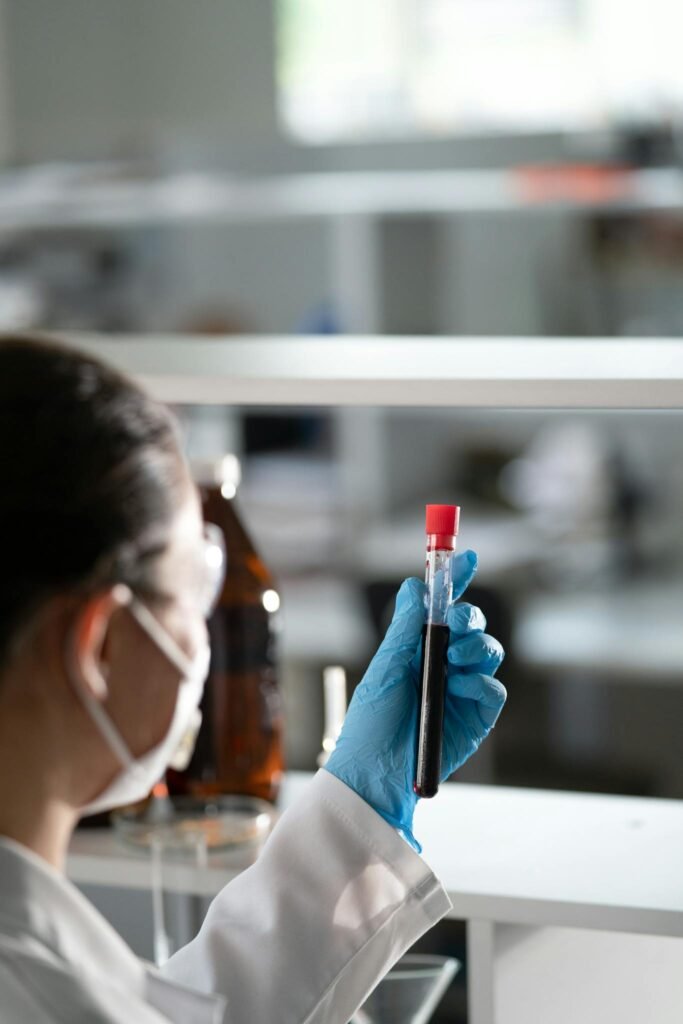 Scientist in lab coat examines a blood sample in test tube, focusing on research.
